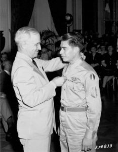 A man awards a medal to a uniformed soldier in a formal ceremony.