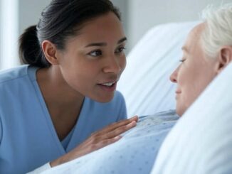 A caregiver attentively listens to an elderly woman in bed.
