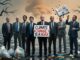 A group of men in suits with a climate change denial sign and apocalyptic background.