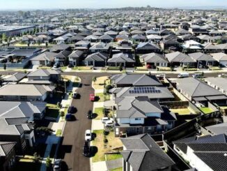A vast suburban neighborhood with rows of houses and parked cars.