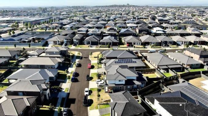 A vast suburban neighborhood with rows of houses and parked cars. A vast suburban neighborhood with rows of houses and parked cars.