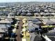 A vast suburban neighborhood with rows of houses and parked cars.