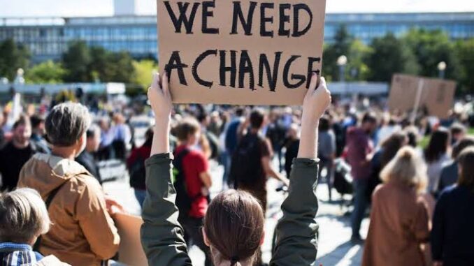 Person holding sign saying 'We Need A Change' at protest. Person holding sign saying 'We Need A Change' at protest.