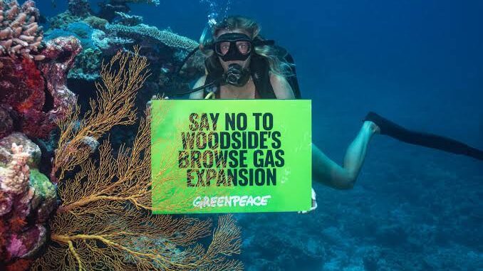 Diver holding a Greenpeace sign against fossil fuel extension underwater. Diver holding a Greenpeace sign against fossil fuel extension underwater.