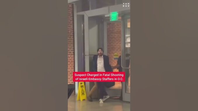 Man in a suit walking out of a building with a news caption about a suspect charged in a fatal shooting.
