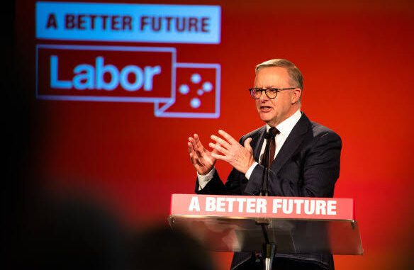 A man in a suit speaks at a podium with a Labor Party backdrop.