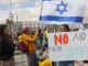 Protesters with Israeli flag and 'No Apartheid' sign.