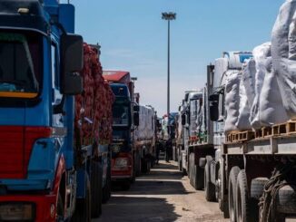 Two rows of trucks loaded with goods parked facing each other.