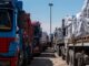 Two rows of trucks loaded with goods parked facing each other.
