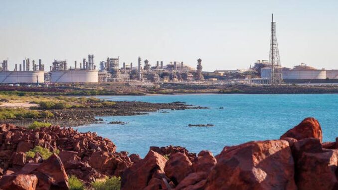 Coastal refinery with industrial structures by the sea under a clear sky.