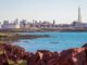 Coastal refinery with industrial structures by the sea under a clear sky.