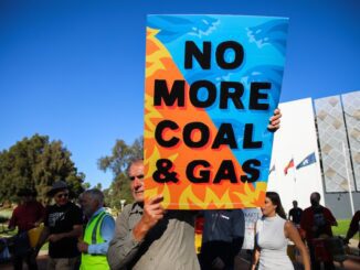 Protester holds a sign saying 'No More Coal & Gas' during a rally.