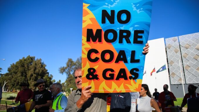 Protester holds a sign saying 'No More Coal & Gas' during a rally.