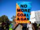 Protester holds a sign saying 'No More Coal & Gas' during a rally.
