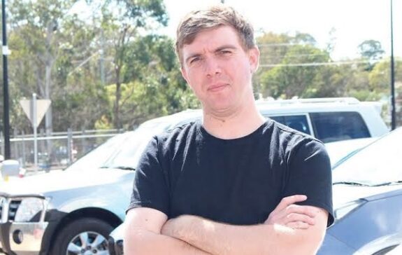 Man in black shirt with arms crossed standing outdoors. Man in black shirt with arms crossed standing outdoors.