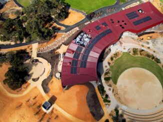 Aerial view of a modern building with curved red roof and surrounding pathways.