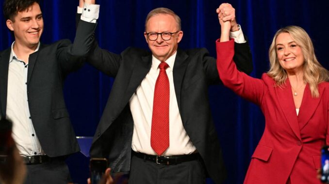 Three people on stage holding hands, celebrating. Three people on stage holding hands, celebrating.