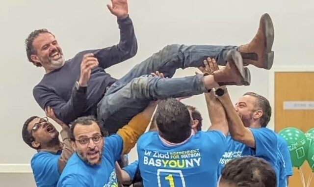 Group lifting a man in celebration, showing joy and teamwork.
