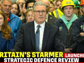 Man giving a speech at a formal event with attentive audience behind him.