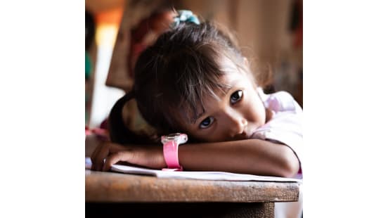 A young girl resting her head on a table, looking thoughtful. A young girl resting her head on a table, looking thoughtful.