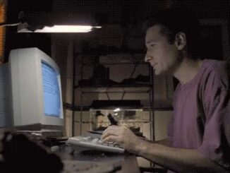 Man typing on a computer keyboard in a dimly lit room.