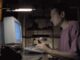 Man typing on a computer keyboard in a dimly lit room.