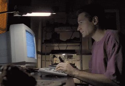 Man typing on a computer keyboard in a dimly lit room.