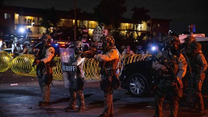 Sheriff deputies in tactical gear stand alert at night during a security operation. Sheriff deputies in tactical gear stand alert at night during a security operation.