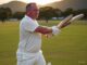 Man playing cricket, focused on the ball.