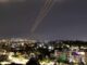 Night cityscape with light trails streaking across the sky.