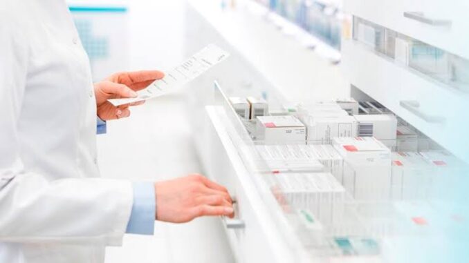 Person selecting a medication box from a pharmacy shelf.