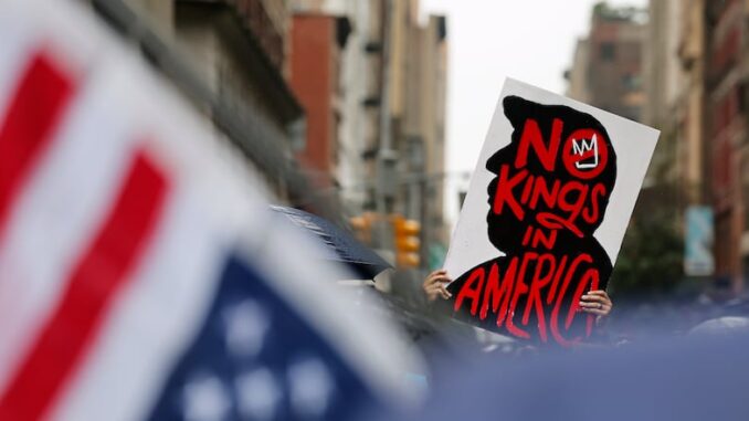 Protest sign reading 'New King is America' with American flags in the foreground. Protest sign reading 'New King is America' with American flags in the foreground.