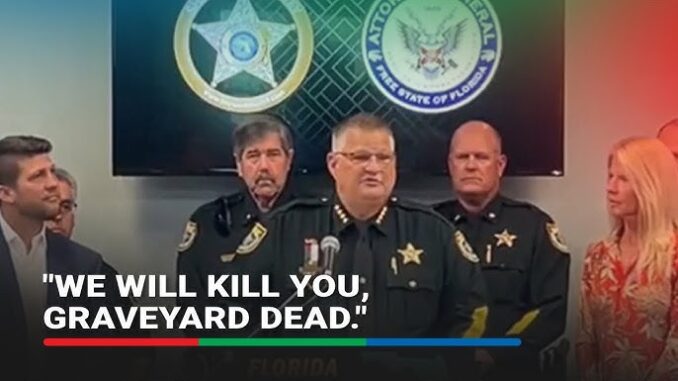 Three stern law enforcement officers at a press briefing.