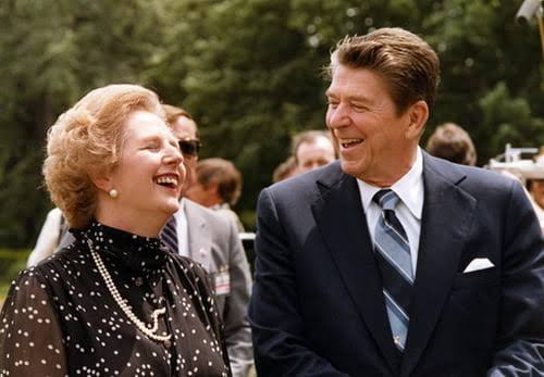 Two people dressed formally, sharing a joyful moment outdoors.