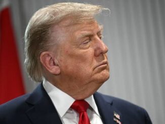 Profile of a serious man in a suit and red tie.
