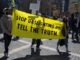 Protesters hold a yellow banner demanding truth about gaslighting.