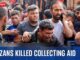 A group mourns over a man killed while collecting aid.