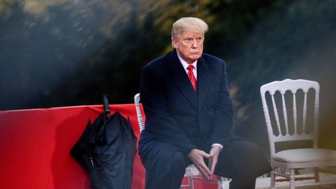A man in a black coat and red tie sitting outdoors, looking thoughtful. A man in a black coat and red tie sitting outdoors, looking thoughtful.