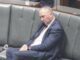 Man in a suit sleeping on a bench.