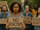 Protesters holding signs against racism at a rally.