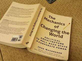 Book titled 'The Mechanics of Changing the Game' on a wooden surface.