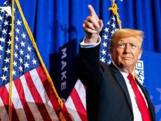 Donald Trump speaking at a podium with US flags behind him.