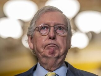 An older man with glasses making a disapproving face.