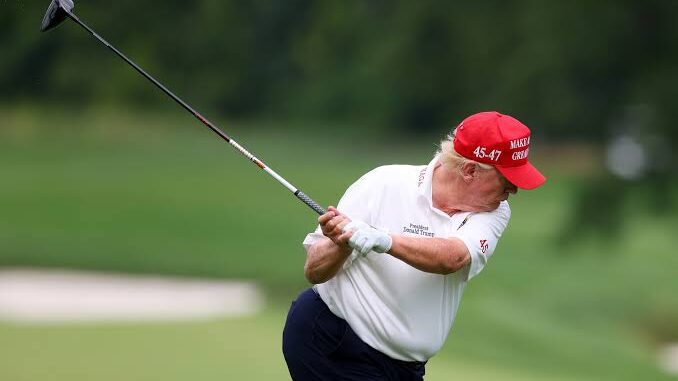 Man in red cap swinging golf club on green course.