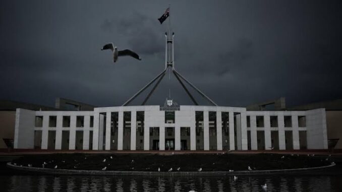 Birds flying over a dark, moody Parliament building at dusk. Birds flying over a dark, moody Parliament building at dusk.