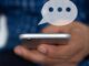 Person holding smartphone with a floating chat bubble above it.