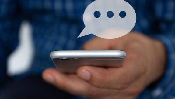Person holding smartphone with a floating chat bubble above it. Person holding smartphone with a floating chat bubble above it.