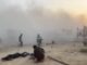 People amidst heavy smoke and debris in a chaotic scene.