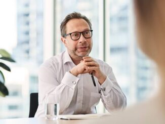 Man in glasses attentively listening during a conversation in an office.