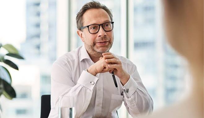 Man in glasses attentively listening during a conversation in an office.
